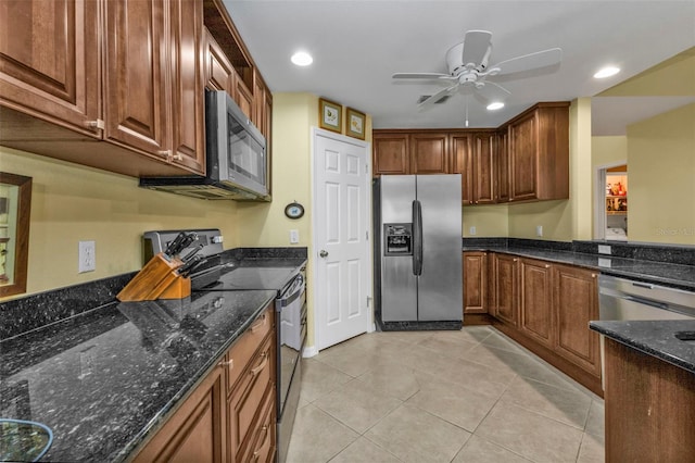 kitchen featuring ceiling fan, stainless steel appliances, dark stone counters, and light tile patterned flooring