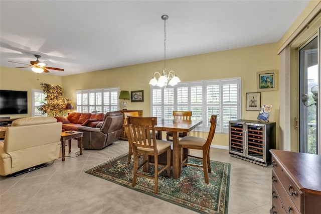 tiled dining area featuring ceiling fan with notable chandelier and beverage cooler