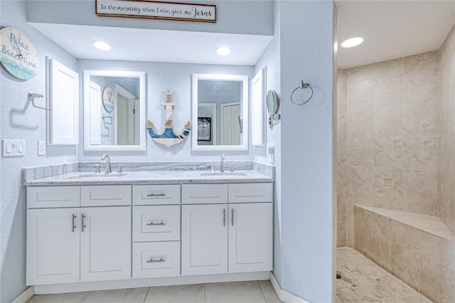 bathroom featuring tile patterned flooring, tiled shower, and vanity