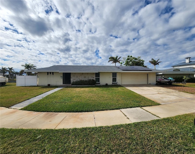 view of front of home with a garage, a front lawn, and solar panels