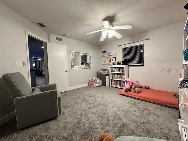 rec room featuring carpet floors, ceiling fan, and a textured ceiling