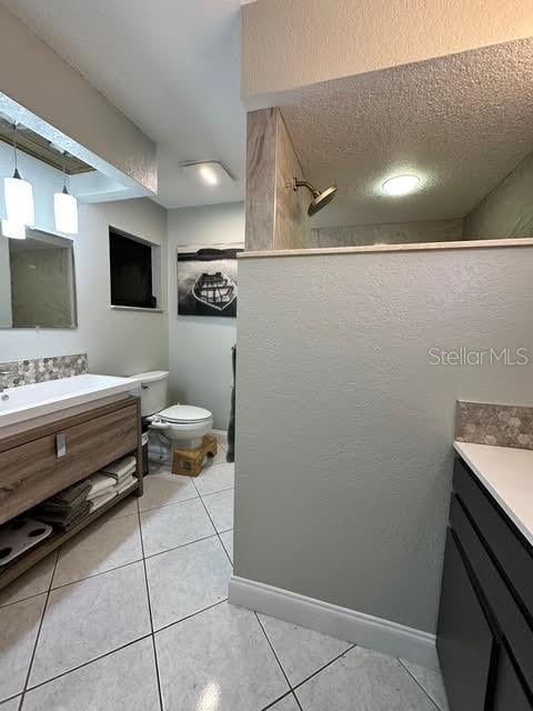 bathroom with walk in shower, tile patterned flooring, vanity, and toilet