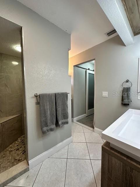 bathroom featuring vanity, tile patterned flooring, and walk in shower