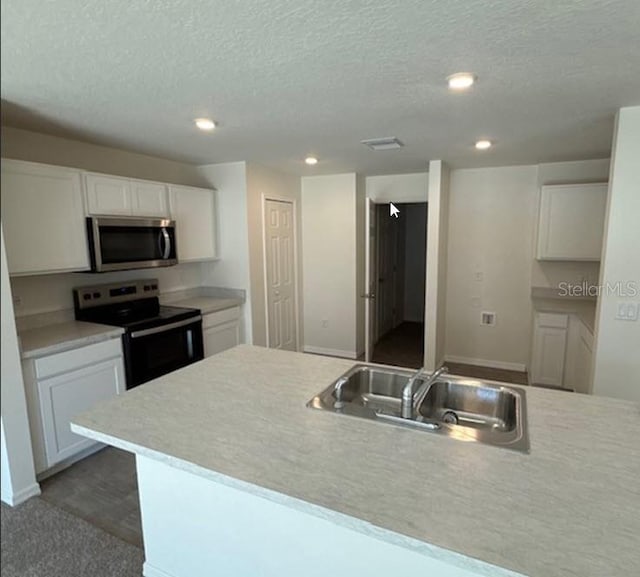 kitchen with sink, white cabinetry, electric range oven, a textured ceiling, and a kitchen island with sink