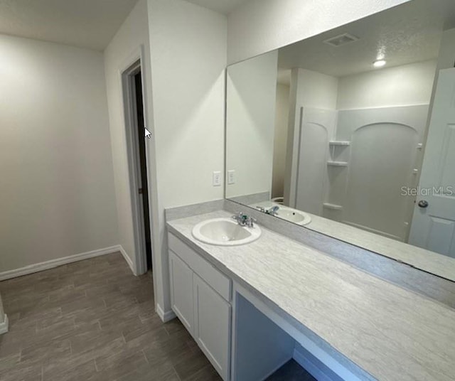 bathroom with hardwood / wood-style flooring, vanity, and a shower