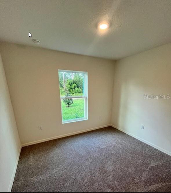 empty room featuring baseboards and dark carpet