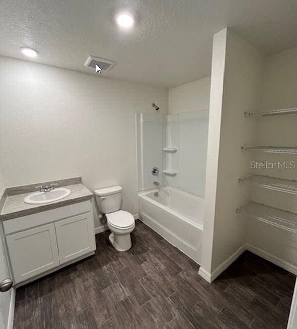 full bathroom with toilet, washtub / shower combination, vanity, a textured ceiling, and wood finished floors