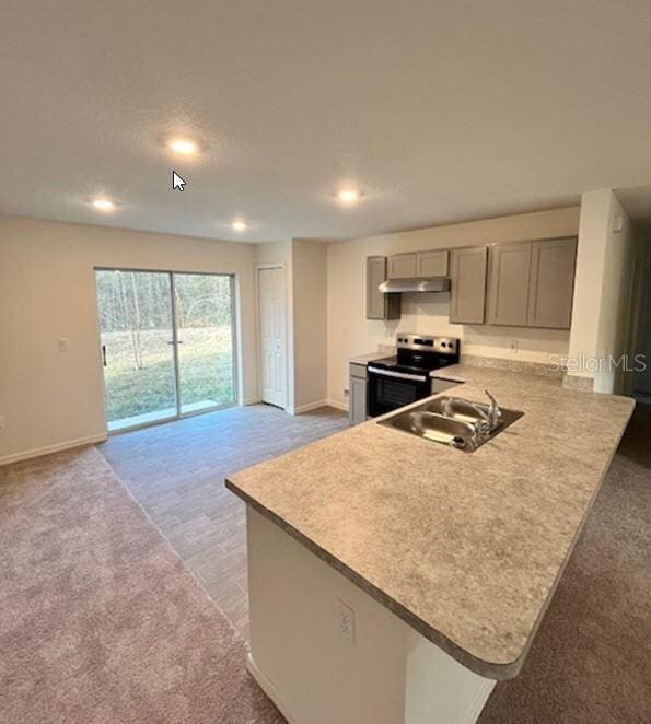 kitchen with electric stove, light colored carpet, a peninsula, gray cabinets, and light countertops