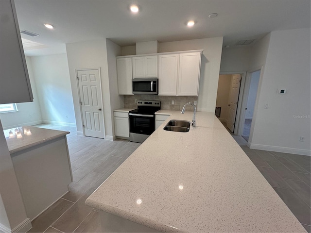 kitchen featuring visible vents, white cabinets, a sink, stainless steel appliances, and backsplash