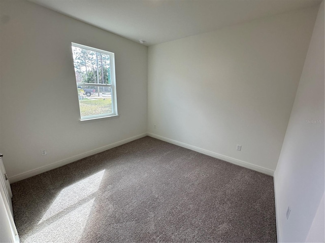 carpeted empty room featuring baseboards