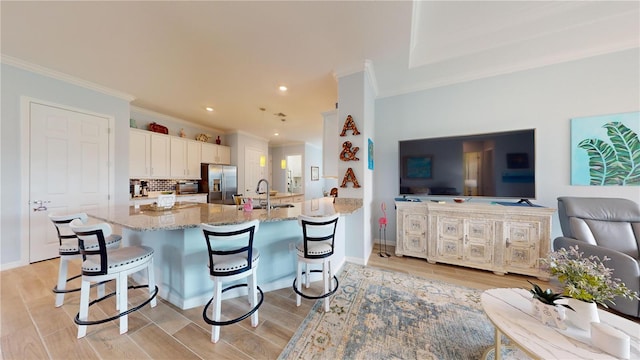 kitchen featuring white cabinets, light stone countertops, a breakfast bar area, hanging light fixtures, and stainless steel fridge with ice dispenser