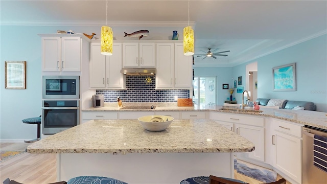 kitchen featuring black appliances, hanging light fixtures, white cabinetry, and a breakfast bar area