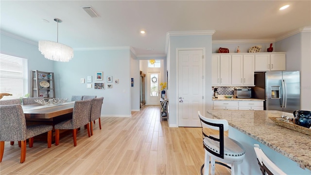 dining room with light hardwood / wood-style floors, crown molding, and a chandelier