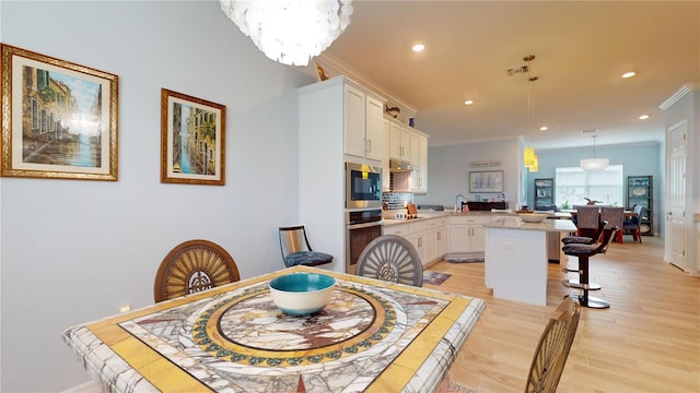 dining area featuring ornamental molding, light hardwood / wood-style floors, and a notable chandelier