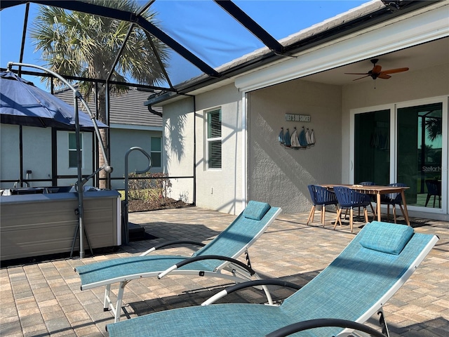 view of patio / terrace featuring ceiling fan, a hot tub, and glass enclosure