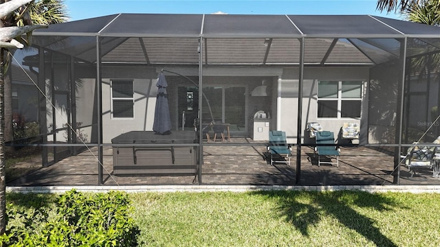 rear view of house featuring a patio area, glass enclosure, and a lawn