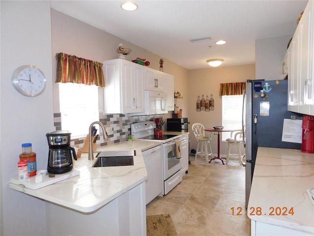 kitchen featuring sink, white cabinetry, white appliances, and a wealth of natural light