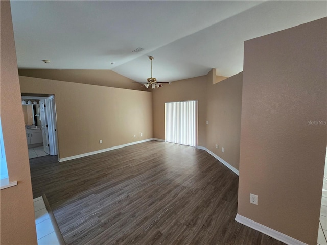 empty room featuring ceiling fan, dark wood-type flooring, and vaulted ceiling