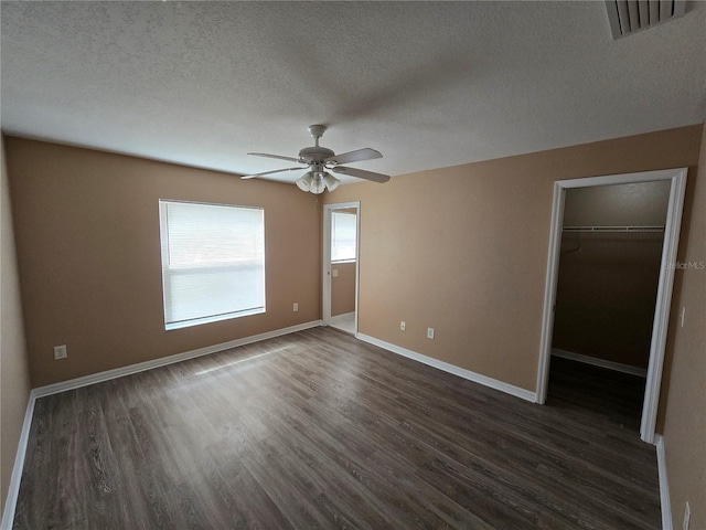 unfurnished bedroom with ceiling fan, dark hardwood / wood-style floors, a walk in closet, and a closet