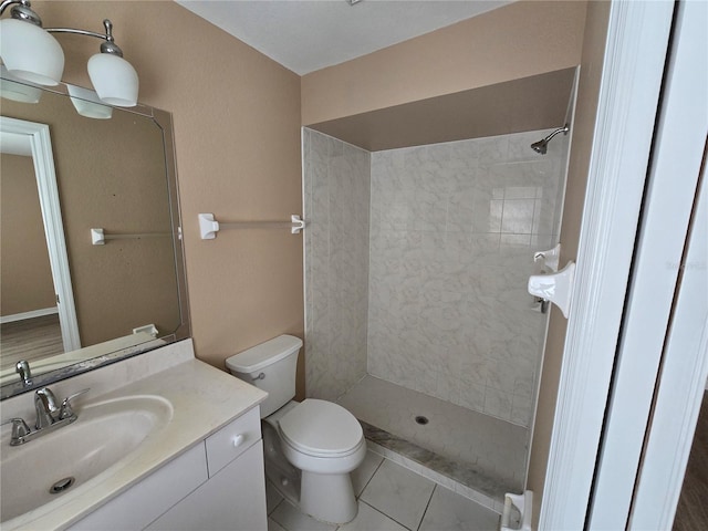 bathroom featuring tile patterned flooring, vanity, tiled shower, and toilet