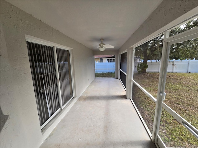 unfurnished sunroom with ceiling fan