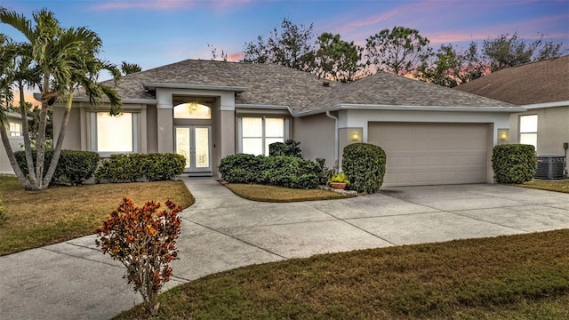 view of front of property with a garage, cooling unit, and a lawn