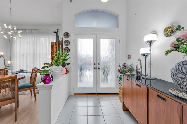 entryway with light tile patterned flooring, a chandelier, and french doors