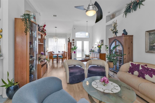 living room with french doors, ceiling fan with notable chandelier, and light wood-type flooring