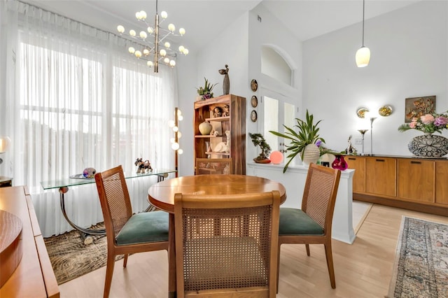 dining room with an inviting chandelier, vaulted ceiling, and light hardwood / wood-style floors