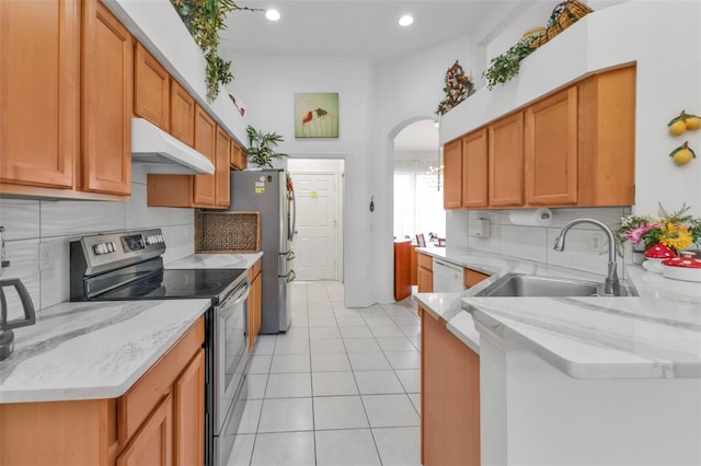 kitchen with appliances with stainless steel finishes, light stone countertops, sink, and decorative backsplash