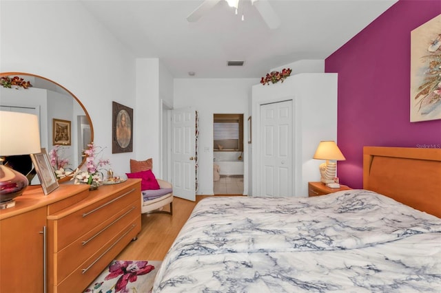 bedroom featuring light wood-type flooring, connected bathroom, ceiling fan, and a closet