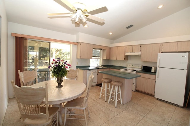 kitchen featuring vaulted ceiling, white appliances, ceiling fan, a breakfast bar area, and light brown cabinetry