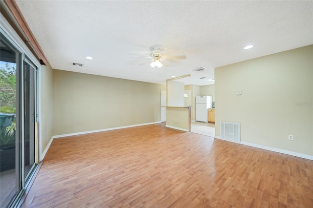 spare room with light wood-type flooring, ceiling fan, and a textured ceiling