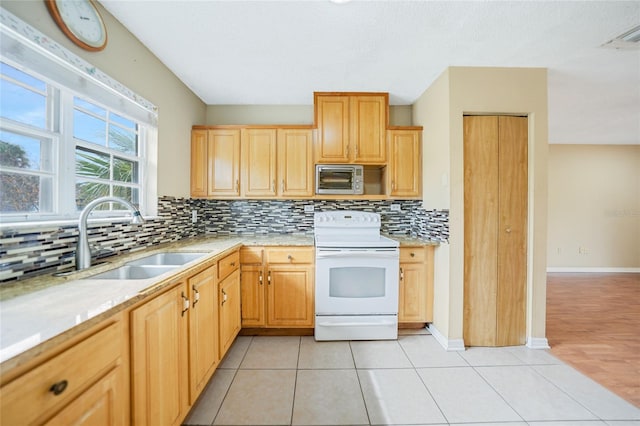 kitchen featuring sink, light brown cabinets, light tile patterned floors, decorative backsplash, and electric range