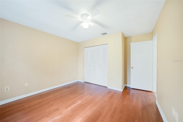 unfurnished bedroom featuring a textured ceiling, ceiling fan, a closet, and hardwood / wood-style floors