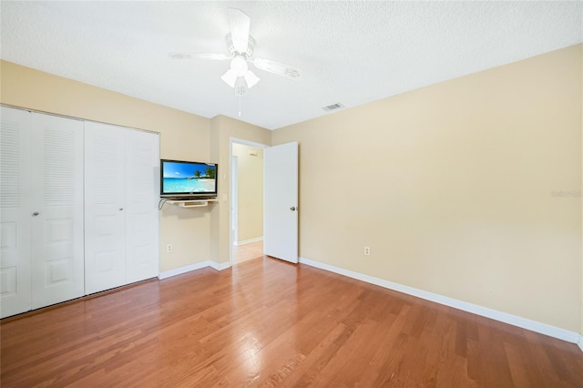 unfurnished bedroom with hardwood / wood-style floors, a closet, ceiling fan, and a textured ceiling