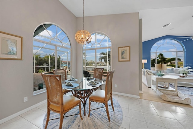 dining area with high vaulted ceiling, light tile patterned floors, a notable chandelier, and a healthy amount of sunlight