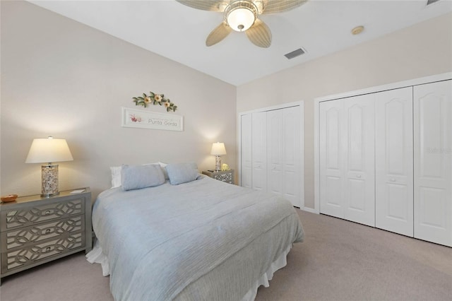 carpeted bedroom with ceiling fan and multiple closets