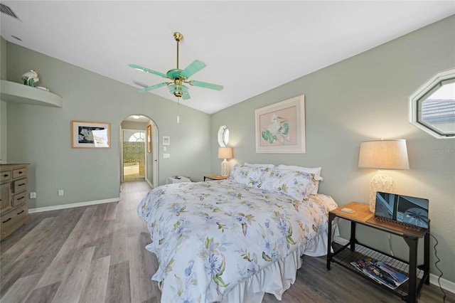 bedroom with ceiling fan, lofted ceiling, connected bathroom, and hardwood / wood-style flooring