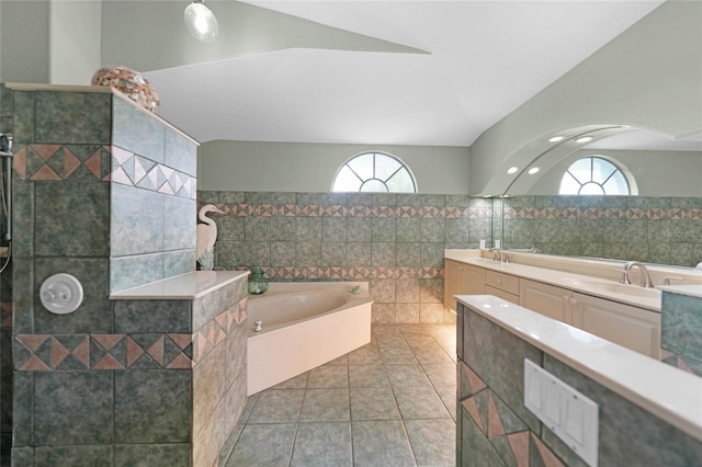 bathroom featuring vanity, a wealth of natural light, tile patterned flooring, and a relaxing tiled tub