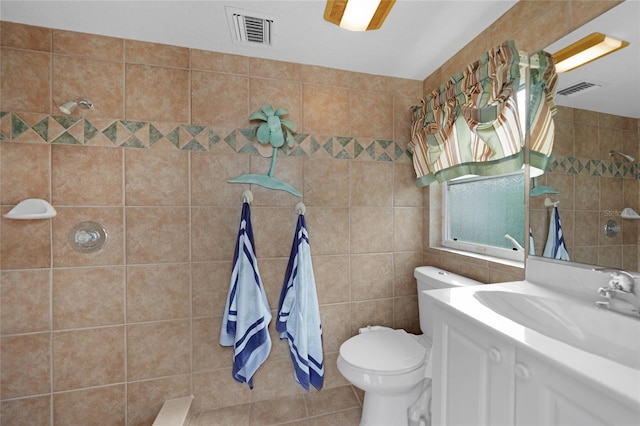 bathroom featuring toilet, a tile shower, tile walls, tile patterned floors, and vanity