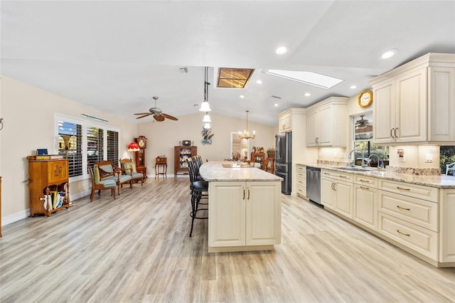 kitchen featuring light stone counters, a kitchen island, pendant lighting, stainless steel appliances, and cream cabinetry