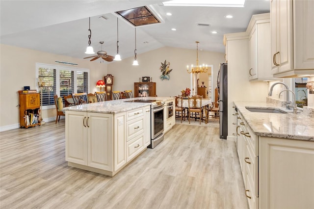 kitchen featuring sink, decorative light fixtures, appliances with stainless steel finishes, a kitchen island, and light stone countertops