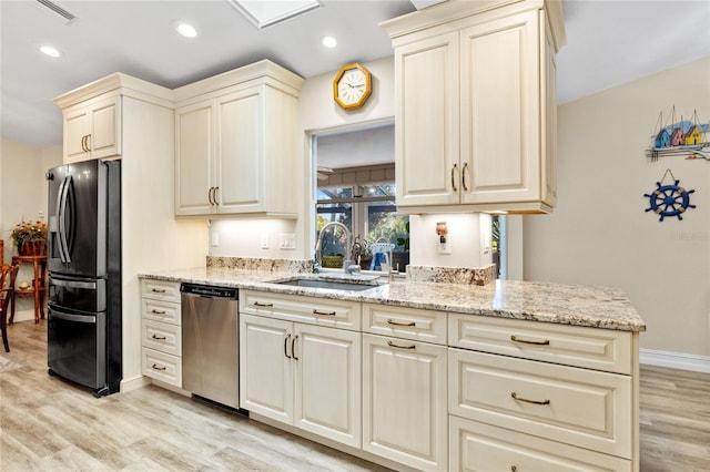 kitchen featuring appliances with stainless steel finishes, sink, light hardwood / wood-style flooring, light stone countertops, and cream cabinetry