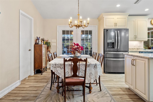 dining space with a notable chandelier and light wood-type flooring