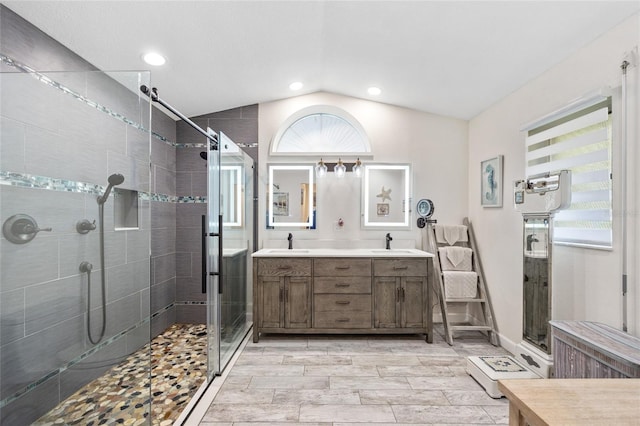 full bathroom featuring a stall shower, vaulted ceiling, a sink, and double vanity