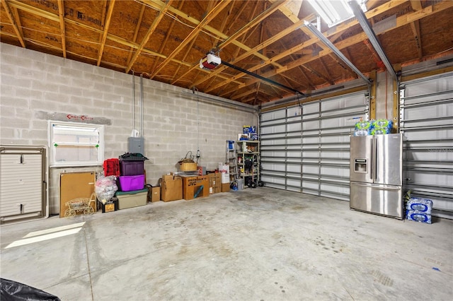 garage with a garage door opener, concrete block wall, and stainless steel refrigerator with ice dispenser