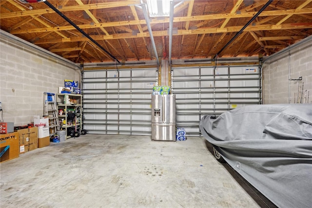 garage with concrete block wall and stainless steel fridge with ice dispenser