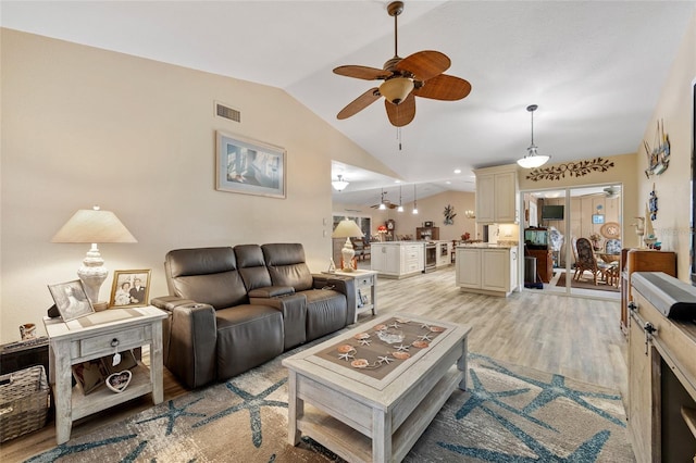 living room featuring lofted ceiling, ceiling fan, visible vents, and light wood-style floors