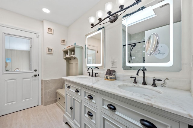 full bath featuring a wainscoted wall, a sink, tile walls, and double vanity